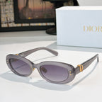 Dior oval sunglasses with dark gray frames, purple lenses, and gold D-logo accents