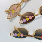 Louis Vuitton sunglasses with gold frame and multicolor logo charms on temple