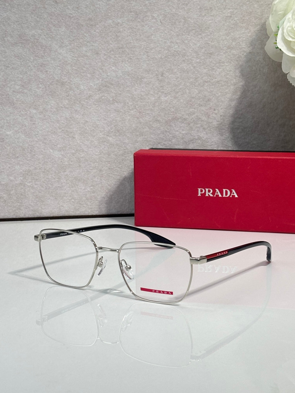 Front view black eyeglasses with clear lenses and red logo accent on temple