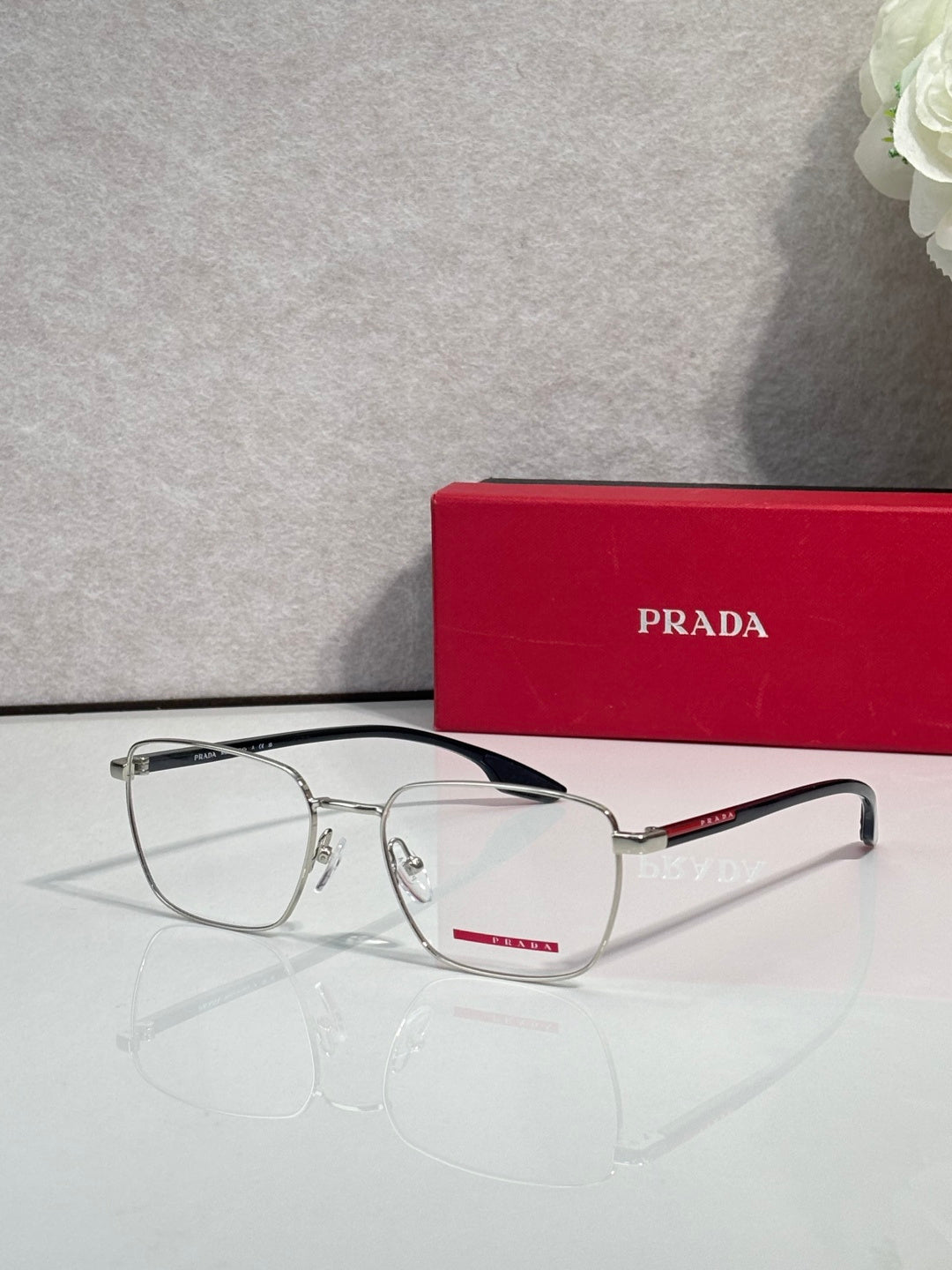 Front view black eyeglasses with clear lenses and red logo accent on temple