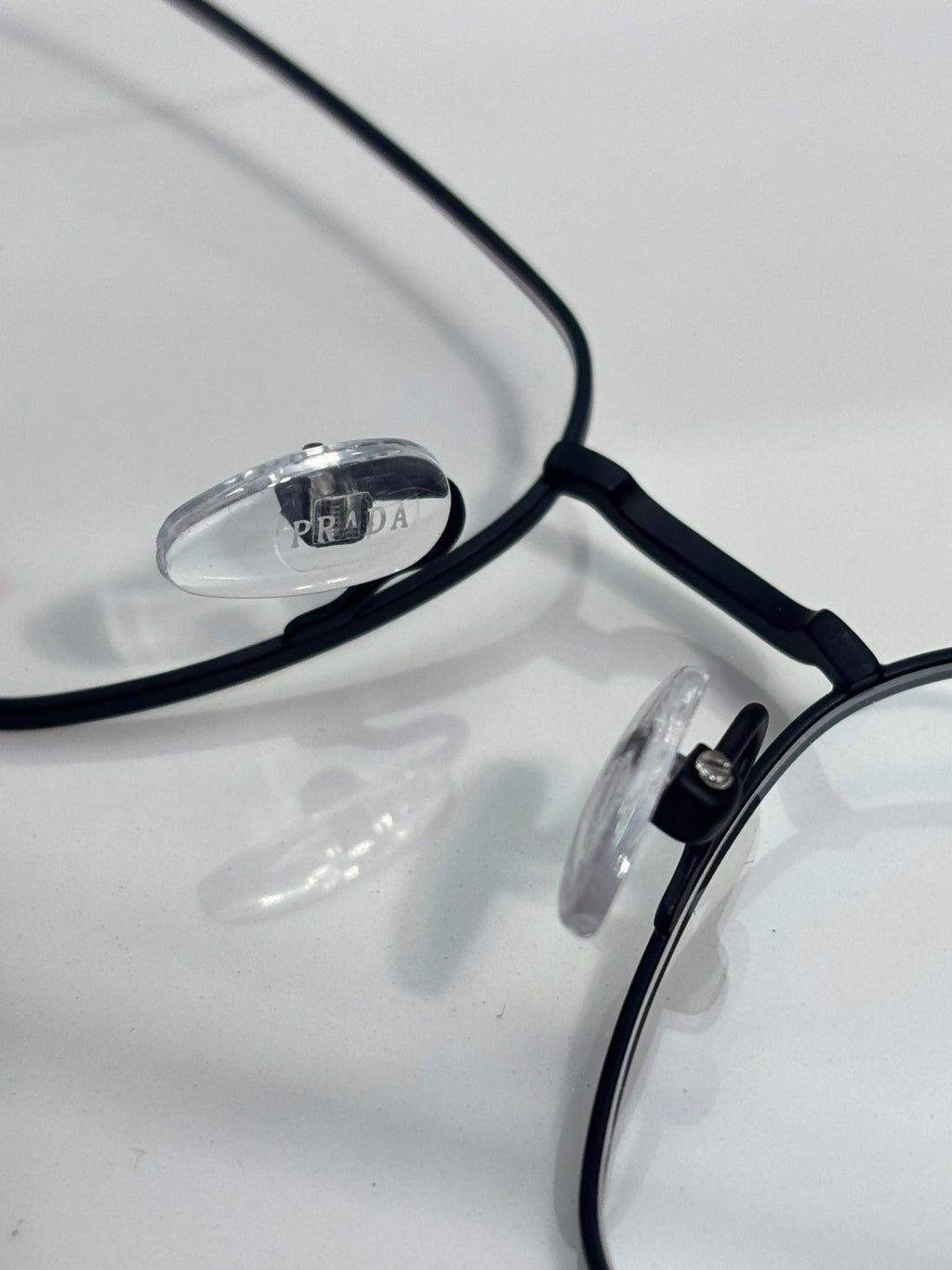 Close-up of black eyeglass frame with clear lenses and Prada logo