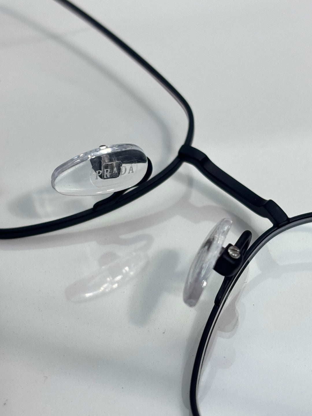 Close-up of black eyeglass frame with clear lenses and Prada logo