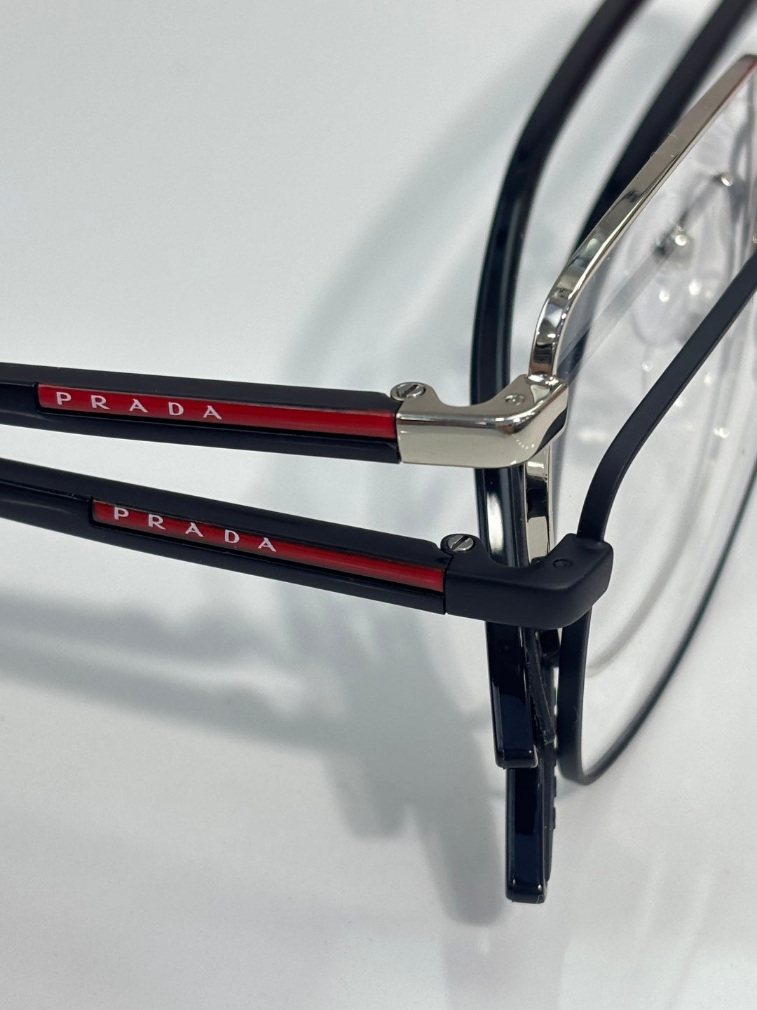 Black eyeglasses with metal bridge and red temple logo on both arms