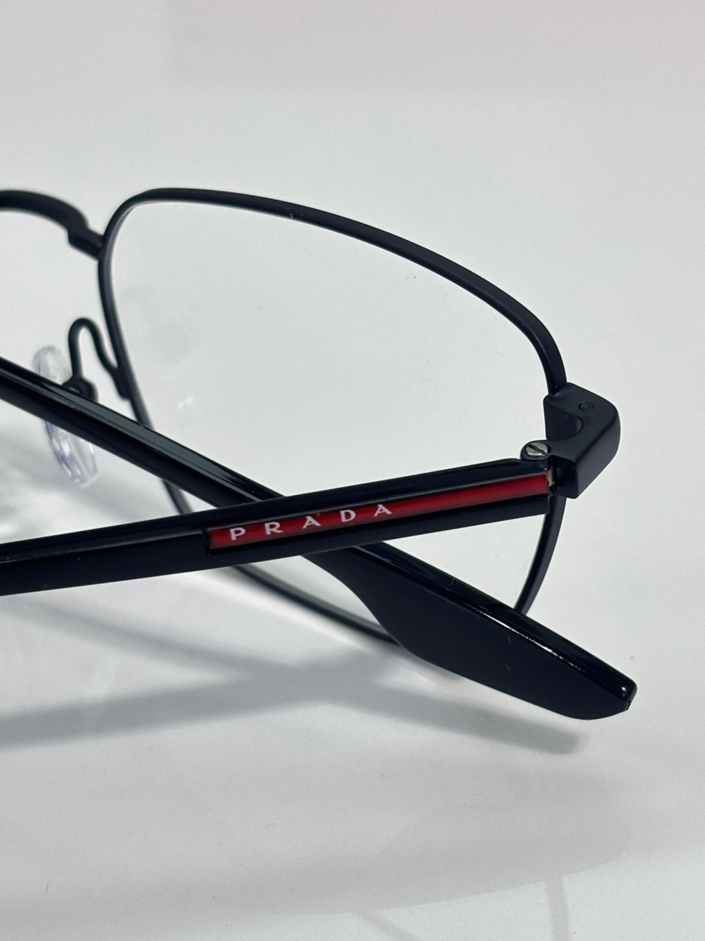 Black eyeglasses with red-and-blue logo bar on temple and clear lenses