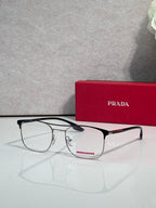 Black full-rim eyeglasses with clear lenses and red logo accents, angled in front of a case.