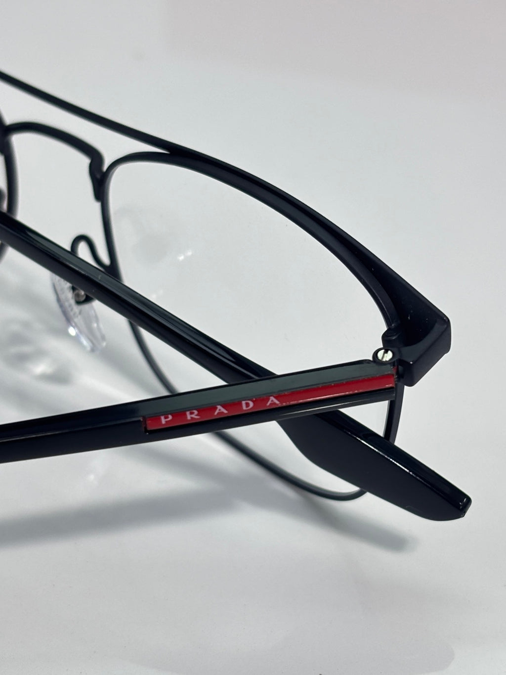 Black eyeglasses close-up with red stripe on the bridge and clear lenses.