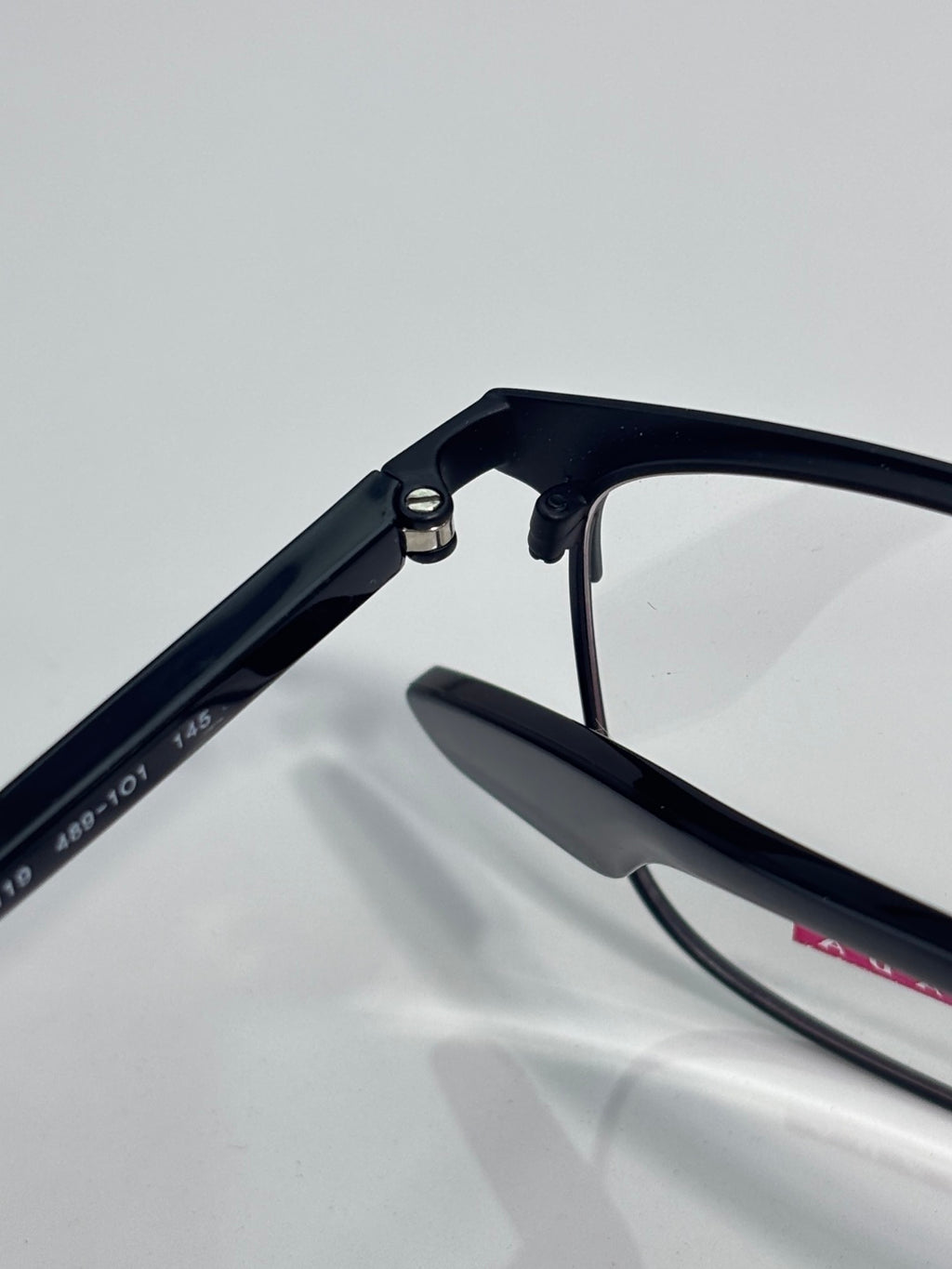 Black eyeglass temple and hinge close-up with clear lens edge visible.