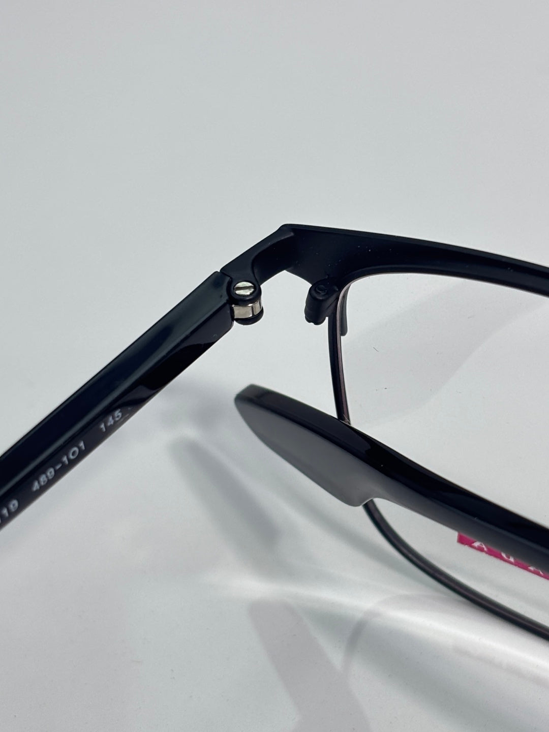 Black eyeglass temple and hinge close-up with clear lens edge visible.