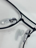 Black eyeglass frame close-up with clear lenses and visible hinge hardware.