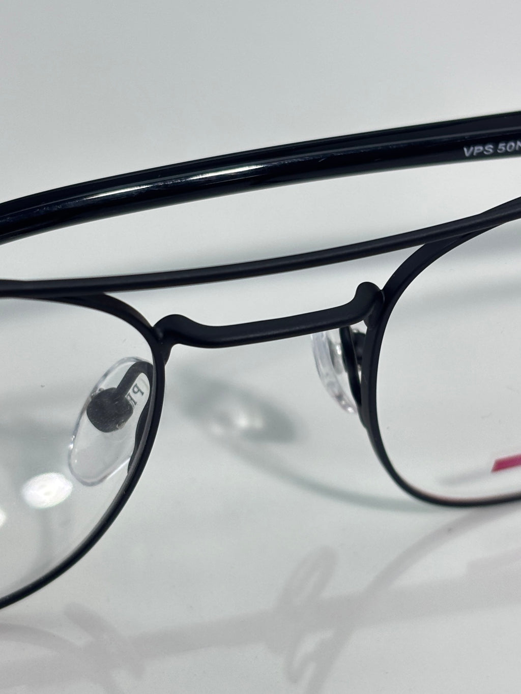 Black eyeglasses close-up with clear lenses and engraved text on the frame arm.
