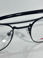 Black eyeglasses close-up with clear lenses and engraved text on the frame arm.