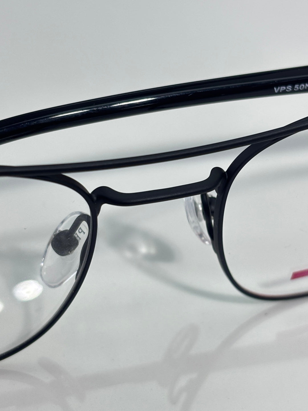 Black eyeglasses close-up with clear lenses and engraved text on the frame arm.