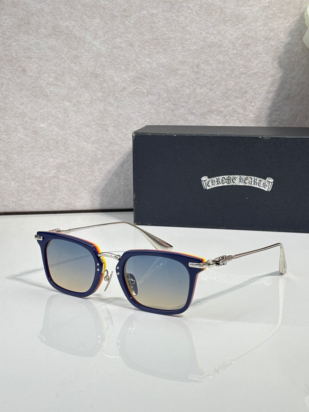 Warm gradient square eyeglasses with blue-tinted lenses and dark frame with gold accents