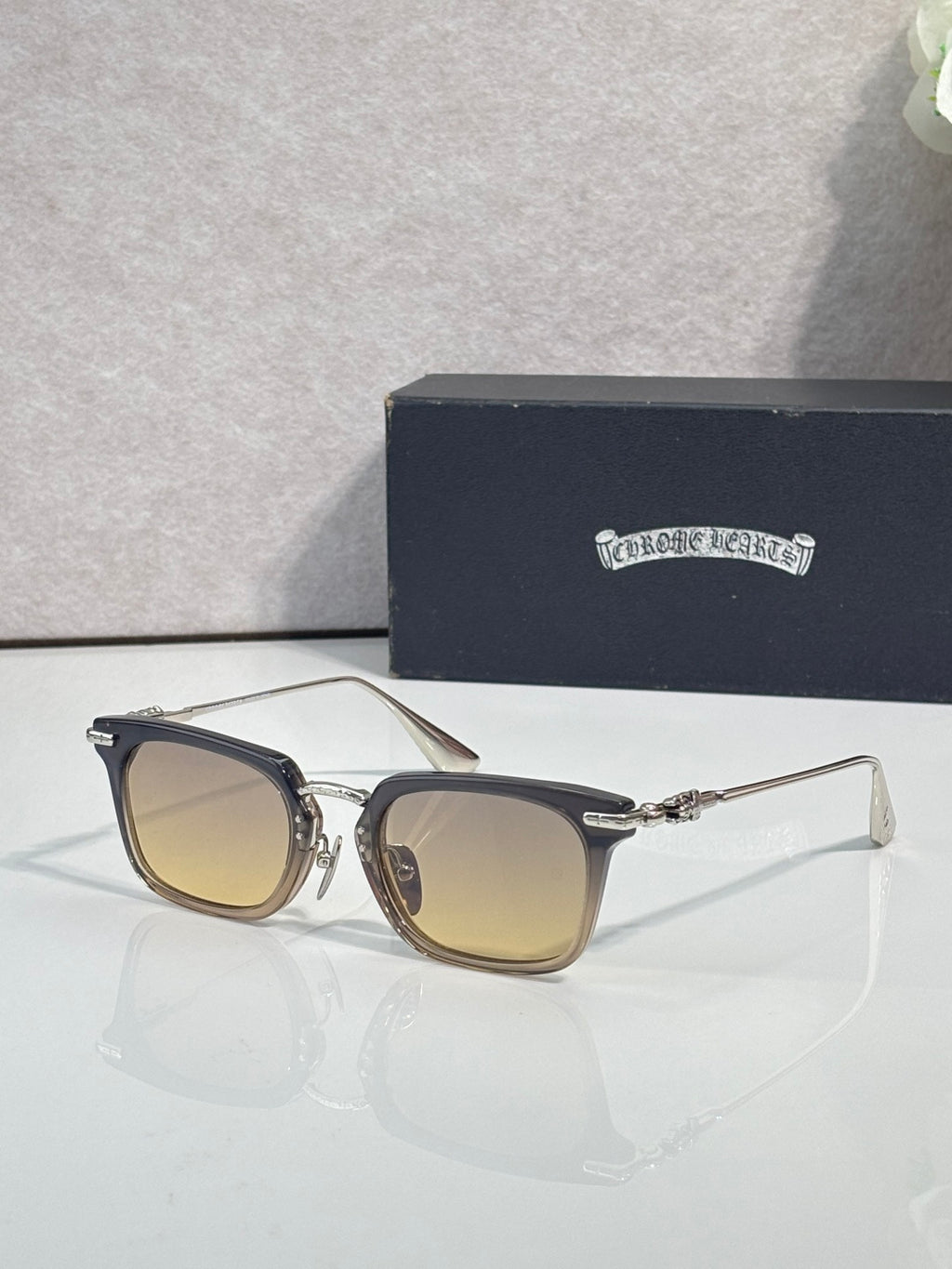 Amber-tinted square eyeglasses with dark frame and silver-tone metal temple details