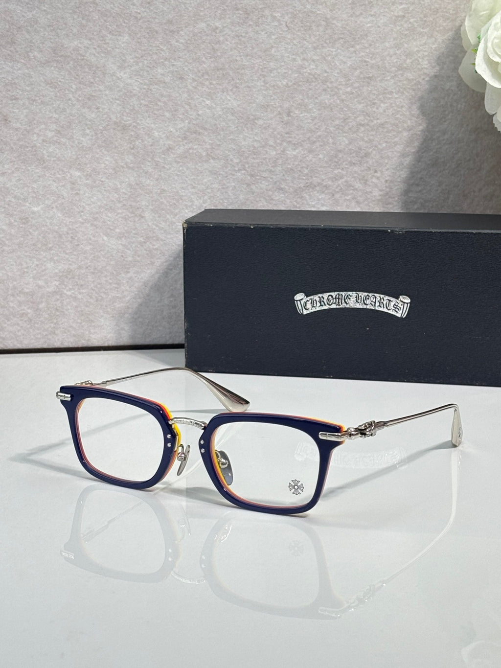 Chrome glasses with dark blue frames, red accents, and clear lenses