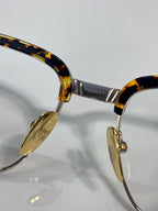 Close-up of tortoise temple and gold hinge on eyeglass frame with clear lenses