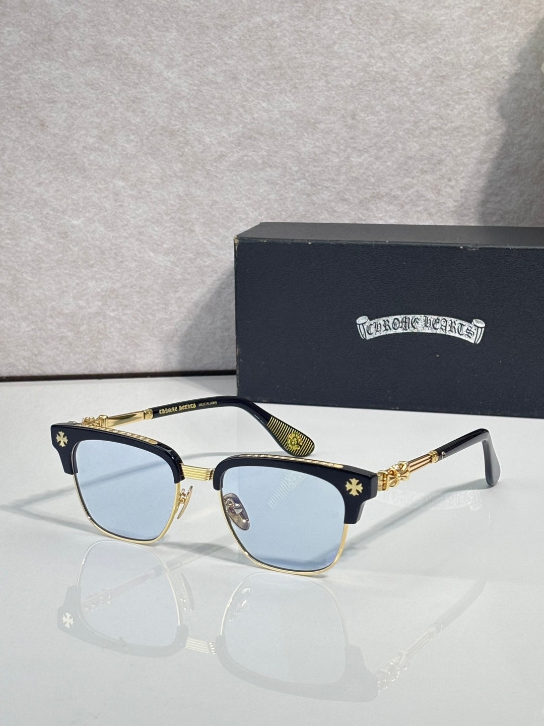 Cat-eye glasses with gold frame, blue-tinted lenses, and patterned temples