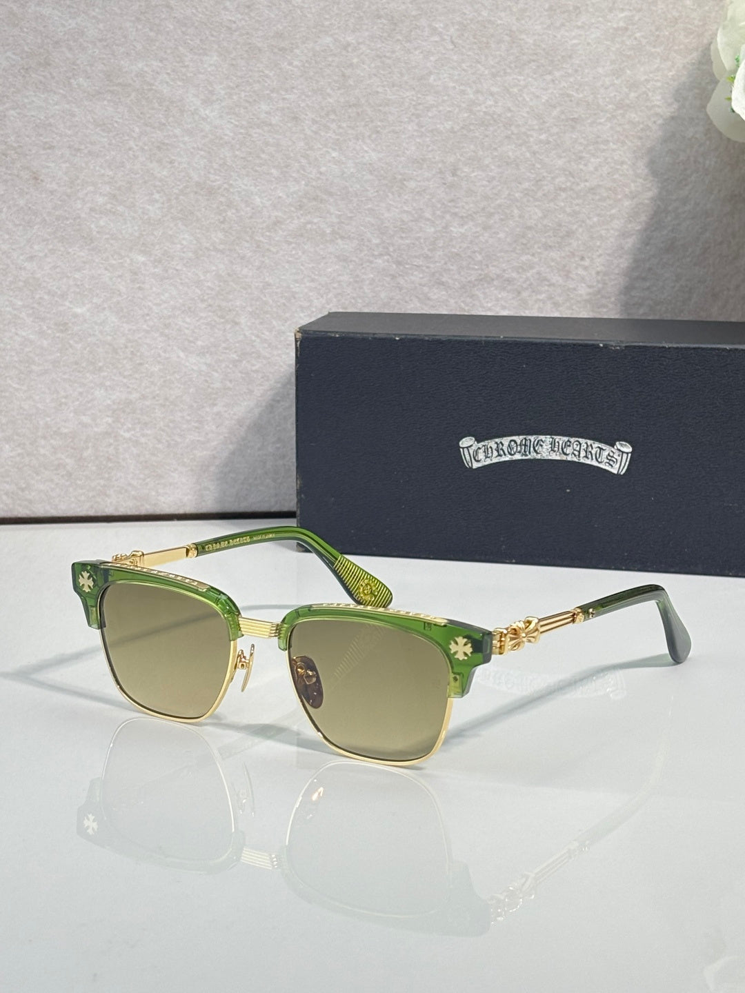 Cat-eye glasses with green frame, gold arms, and light-tinted lenses