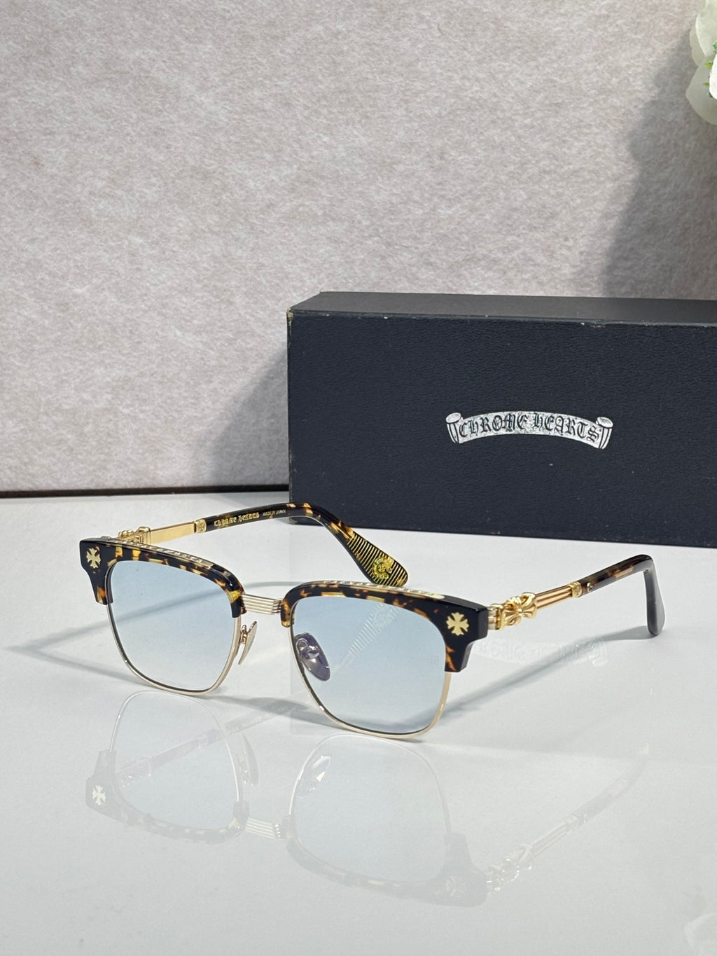 Cat-eye glasses with gold-tortoise frame, gold arms, and blue-tinted lenses