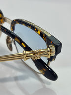 Glasses close-up: tortoise temple with gold hinge and bow-style metal detail