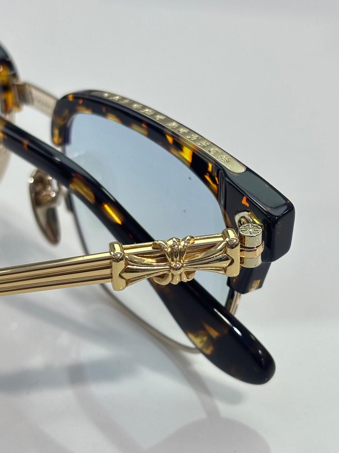 Glasses close-up: tortoise temple with gold hinge and bow-style metal detail