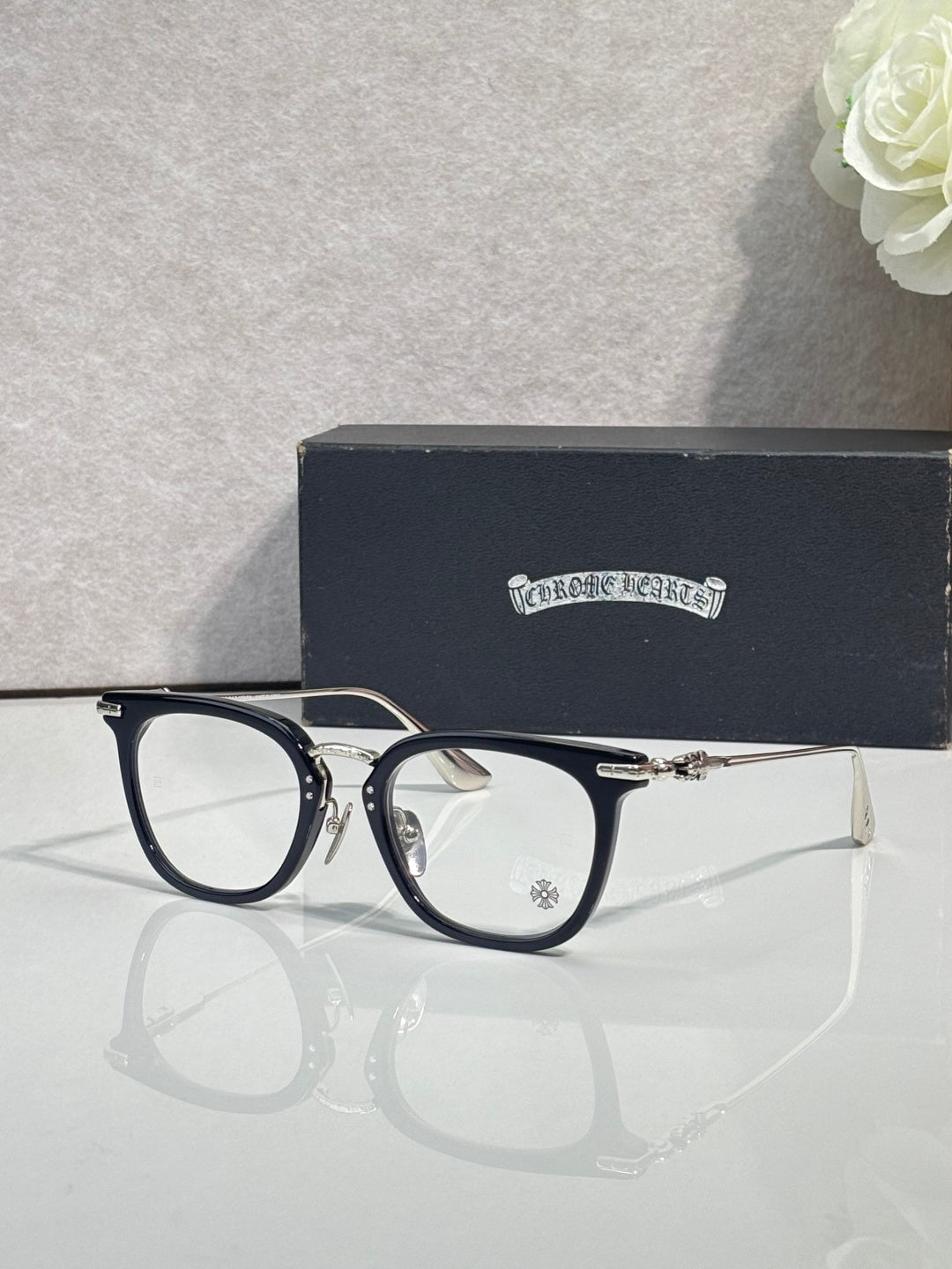 Chrome eyeglasses with dark blue frames and gold temples, clear lenses