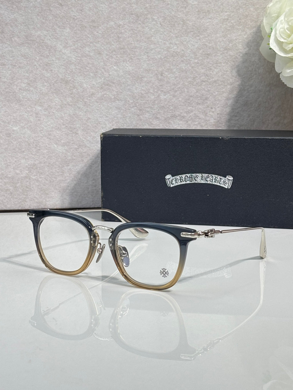 Chrome eyeglasses with dark blue frames and gold metal bridge, clear lenses