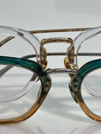 Chrome eyeglasses close-up with green and gold frames and clear lenses