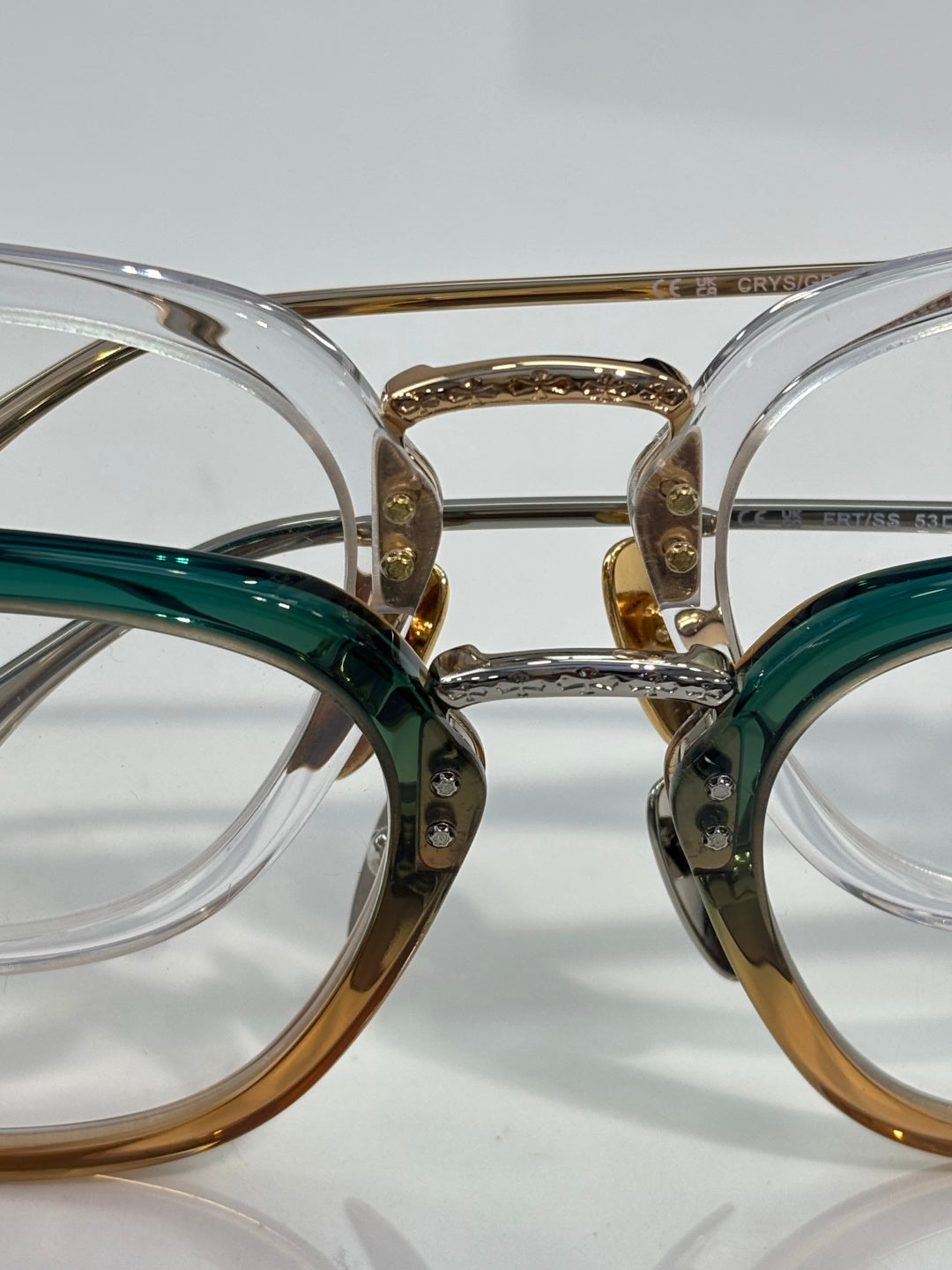 Chrome eyeglasses close-up with green and gold frames and clear lenses