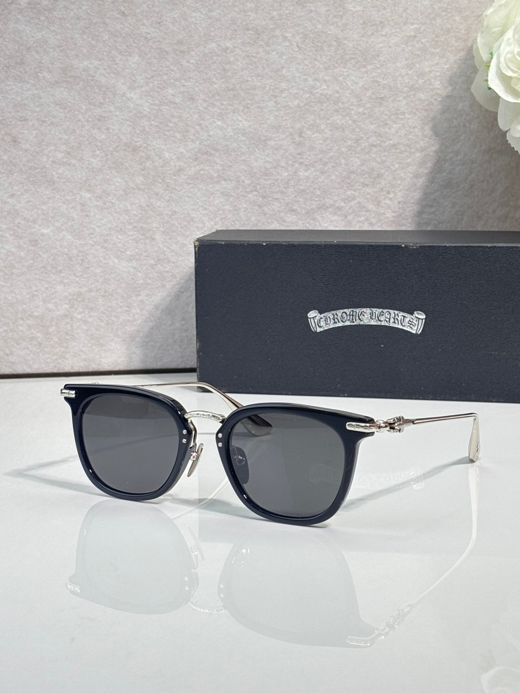 Chrome sunglasses with dark navy frames, gold-tone hinges, and tinted lenses