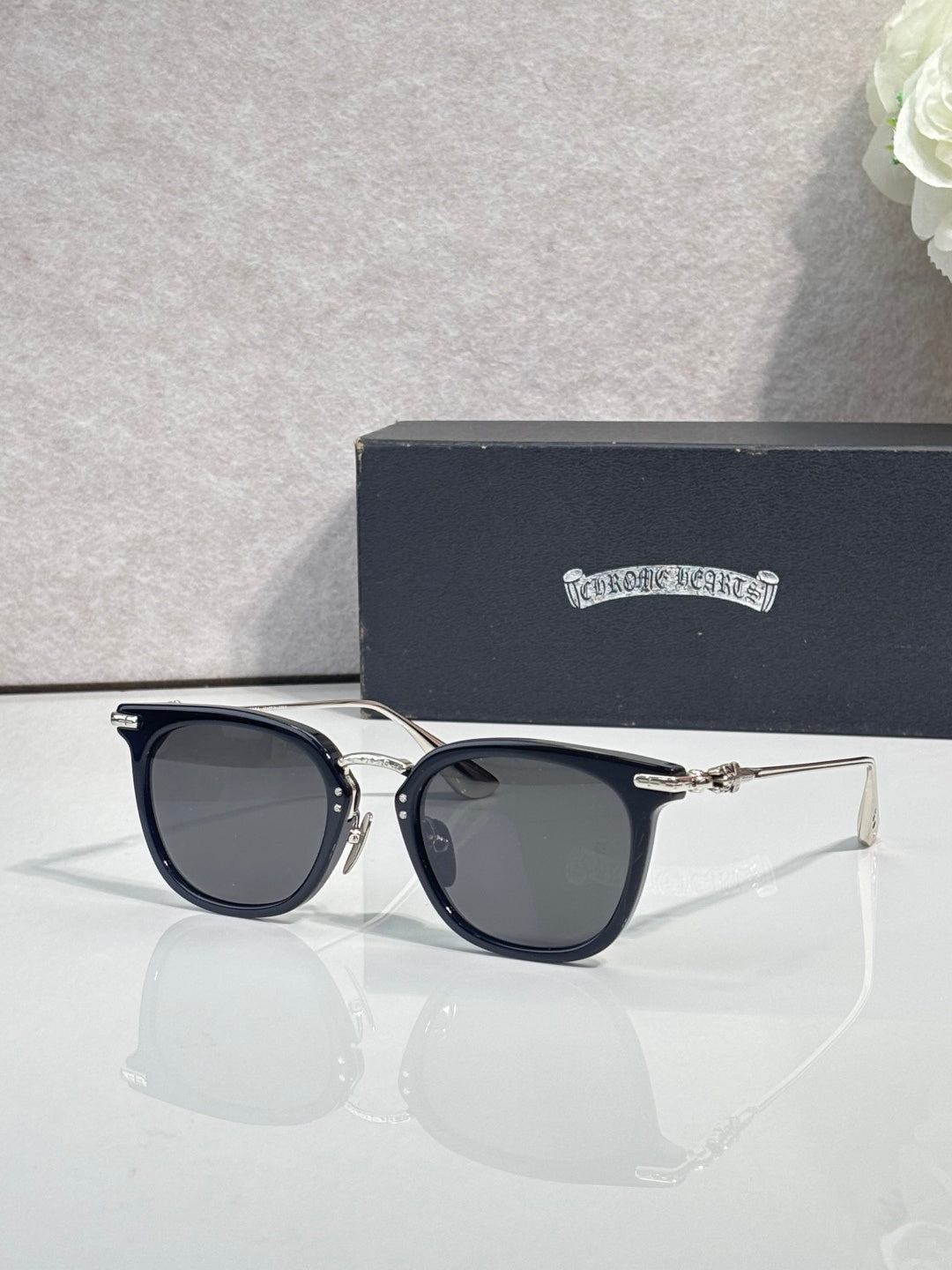 Chrome sunglasses with dark navy frames, gold-tone hinges, and tinted lenses