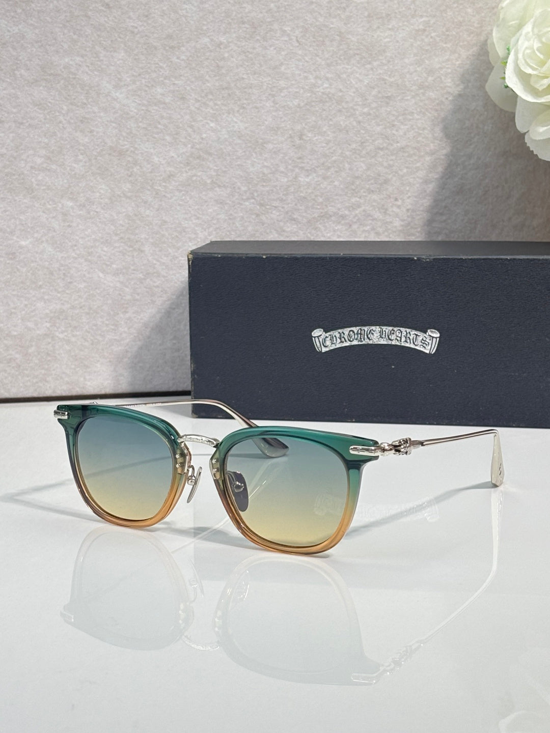 Chrome sunglasses with green-tinted frames, gold-tone accents, and tinted lenses