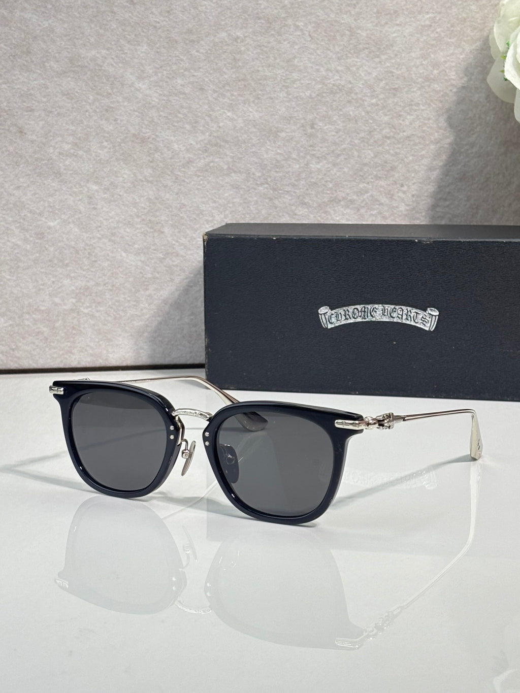 Chrome sunglasses with dark navy cat-eye frames and gold-tone temple tips