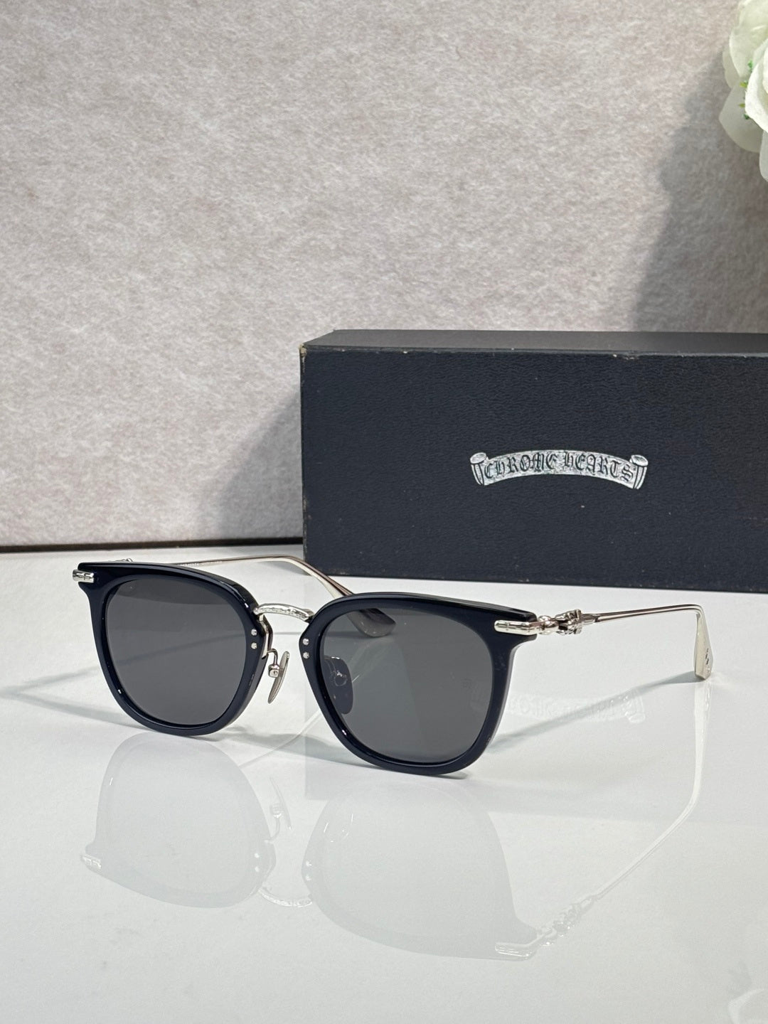 Chrome sunglasses with dark navy cat-eye frames and gold-tone temple tips
