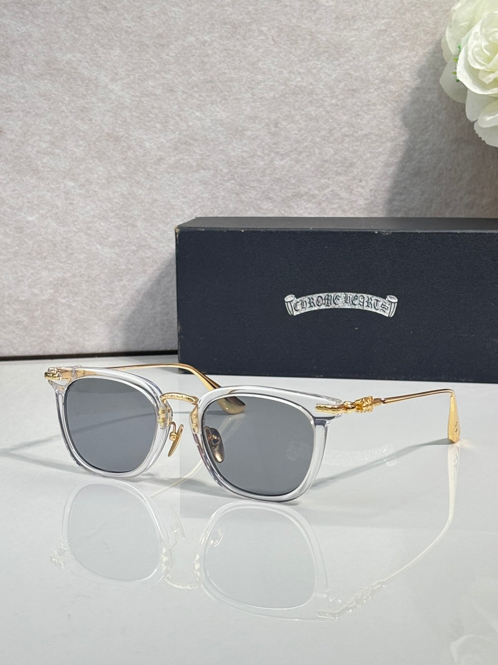 Chrome sunglasses with light gold frames, gray tinted lenses, and gold-tone hinges