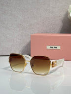 Gold-tone sunglasses with brown gradient lenses and green temple tips, oversized angular shape