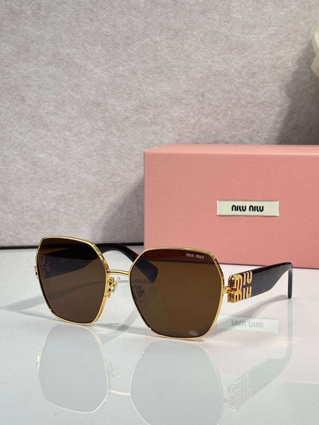 Gold-tone sunglasses with dark brown lenses and green temples, chunky angular frame