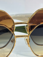 Gold-tone sunglasses with circular lenses and green bridge, front view close-up