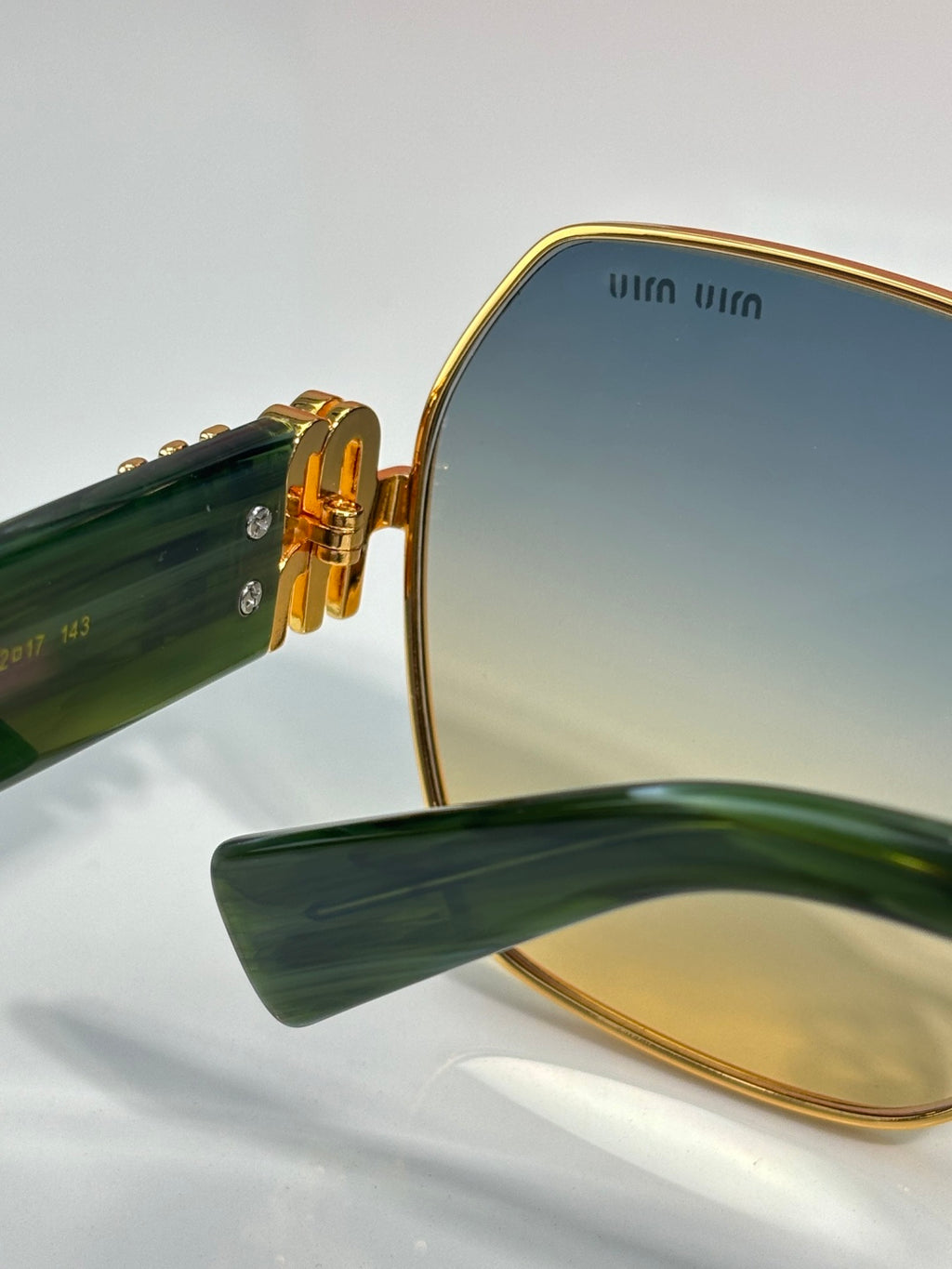 Gold-tone sunglasses side view with dark lenses and green temple arm