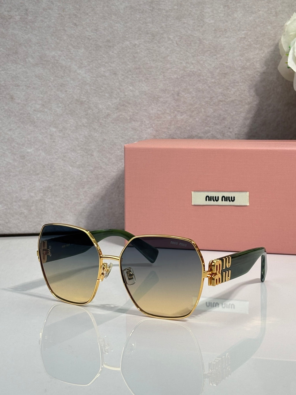 Gold-tone sunglasses with tinted lenses and green temples, bold angular design