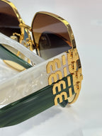 Gold-tone sunglasses showing stacked logo on temple and dark lens frame