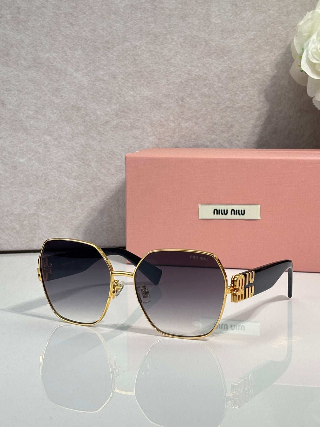 Gold-tone sunglasses with dark lenses and green temples, angular oversized frame