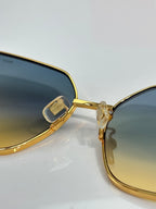 Gold-tone sunglasses showing lens edge, clear hinge piece, and thin frame detail