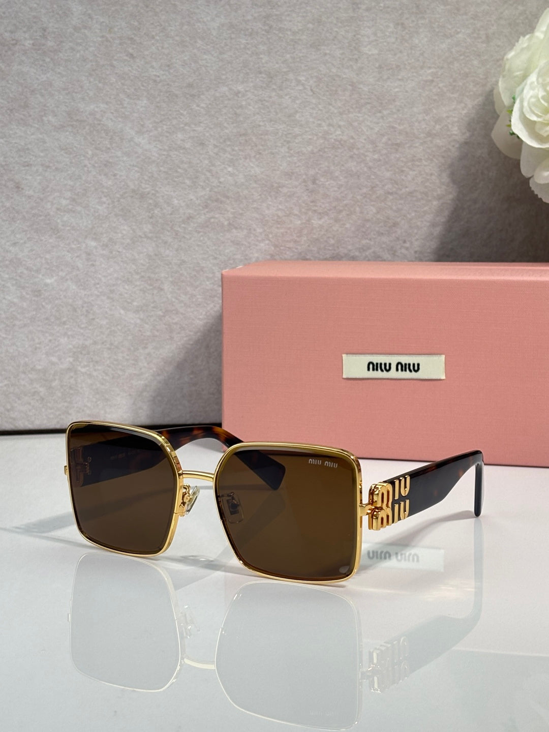 Gold square sunglasses with dark gradient lenses, on display with logo temples