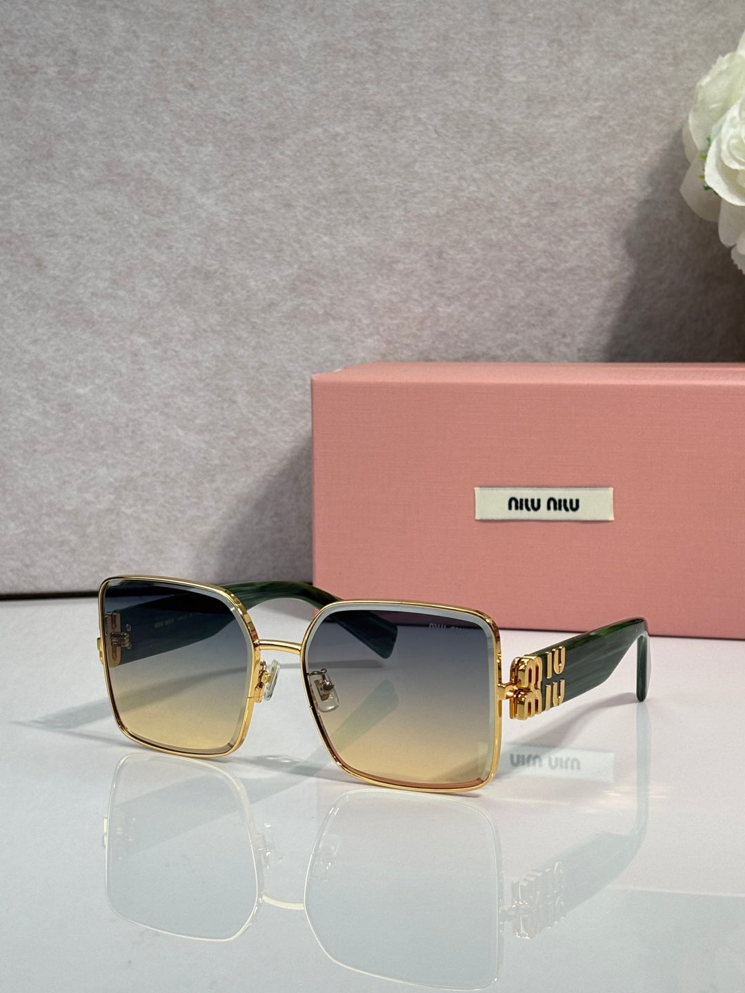 Gold square sunglasses with dark lenses and green striped temple accents