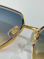 Close-up of gold sunglasses hinge with clear temple details and dark lens edge