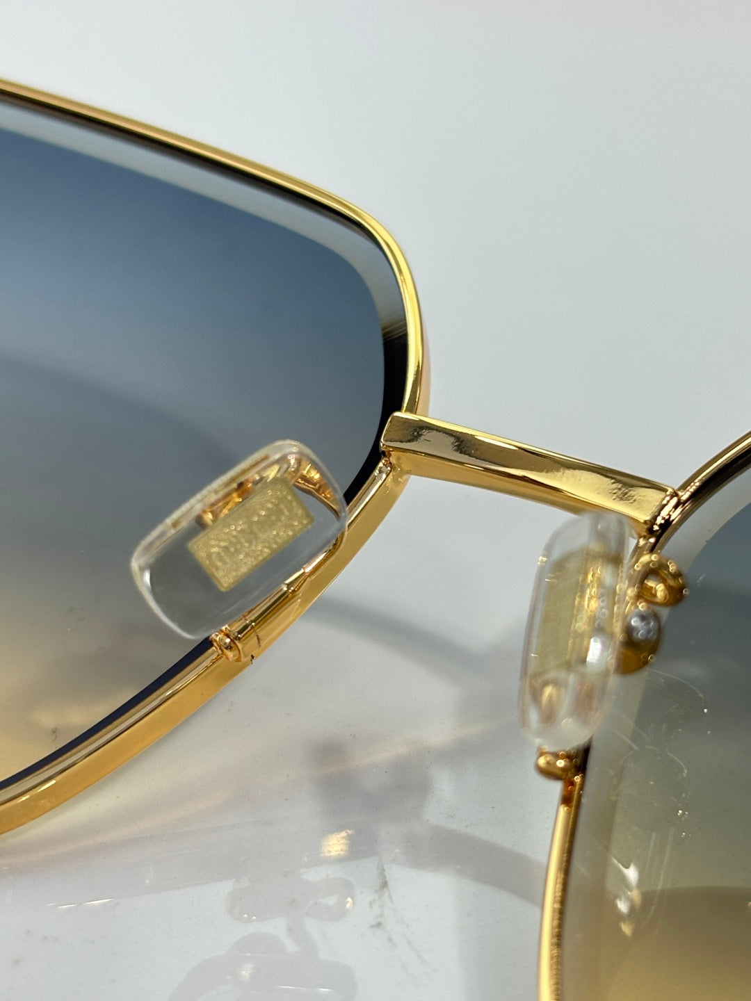Close-up of gold sunglasses hinge with clear temple details and dark lens edge