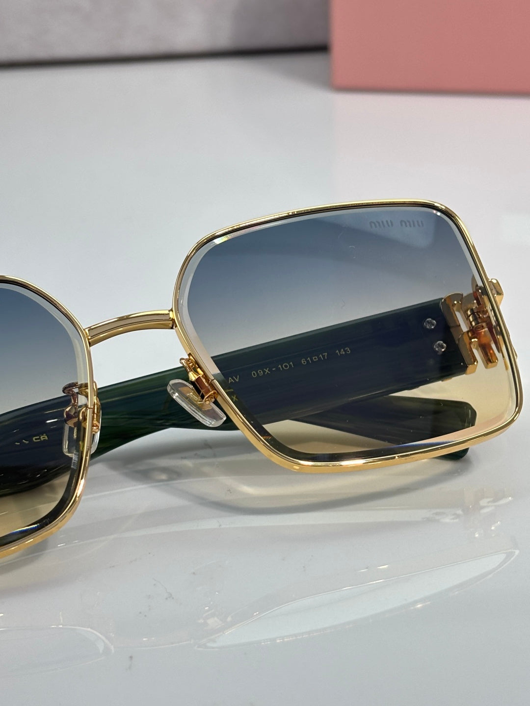 Side profile of gold sunglasses with dark lenses and green temple bar detail