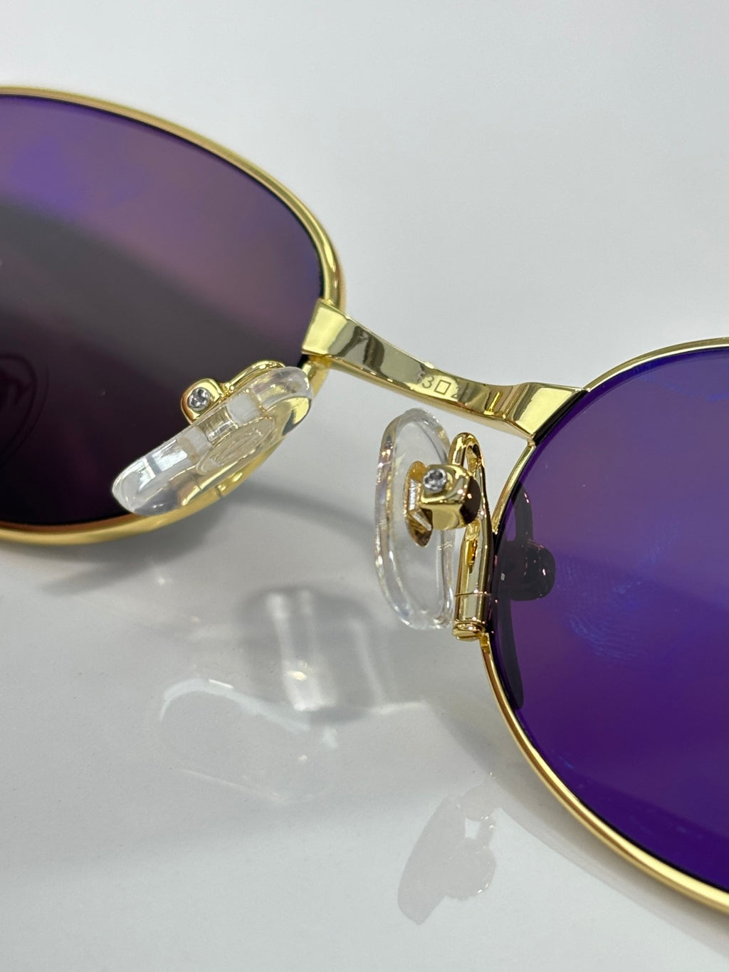 Gold eyeglasses with purple-tinted lenses and jeweled hinge detail