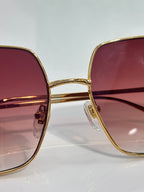 Front view sunglasses with gold-tone frames and maroon gradient lenses